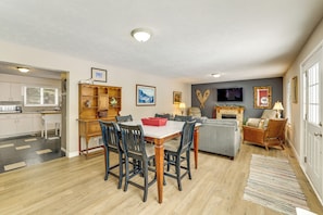 A dining area with a table and chairs, a kitchen with cabinets, a fireplace, and a living room with a sofa and a television. - Family Escape in Crystal Mtn Resort! 13 Mi to Lake (Thompsonville)