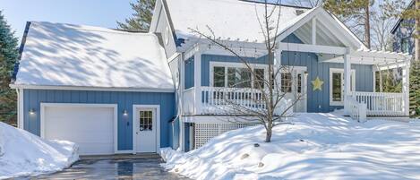 A two-story house with a garage, a covered porch, and a snow-covered driveway.
