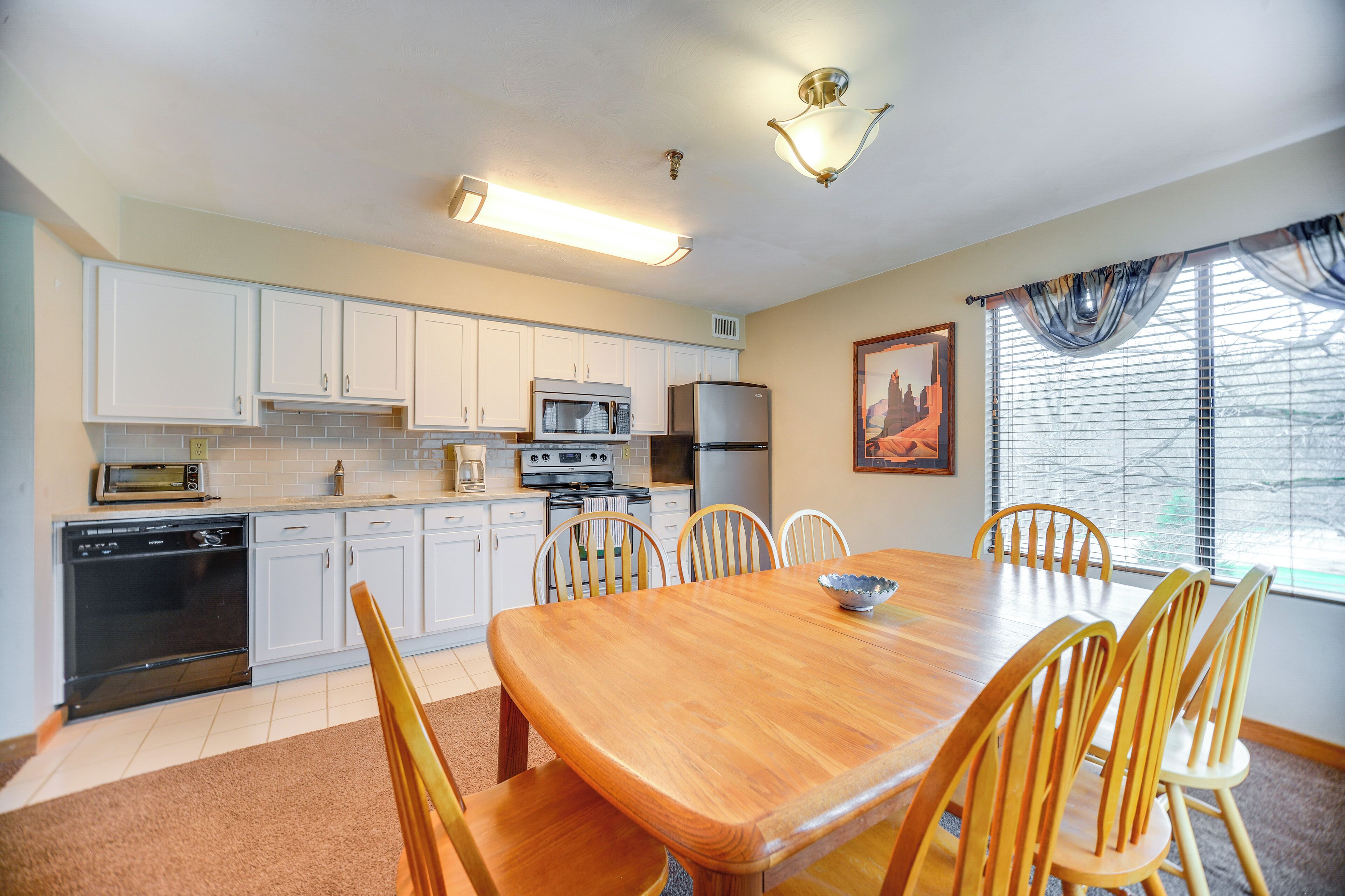 A kitchen with white cabinets, a wooden dining table, and chairs.