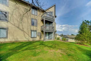 A multi-story residential building with a balcony, a well-maintained lawn, and a clear sky.