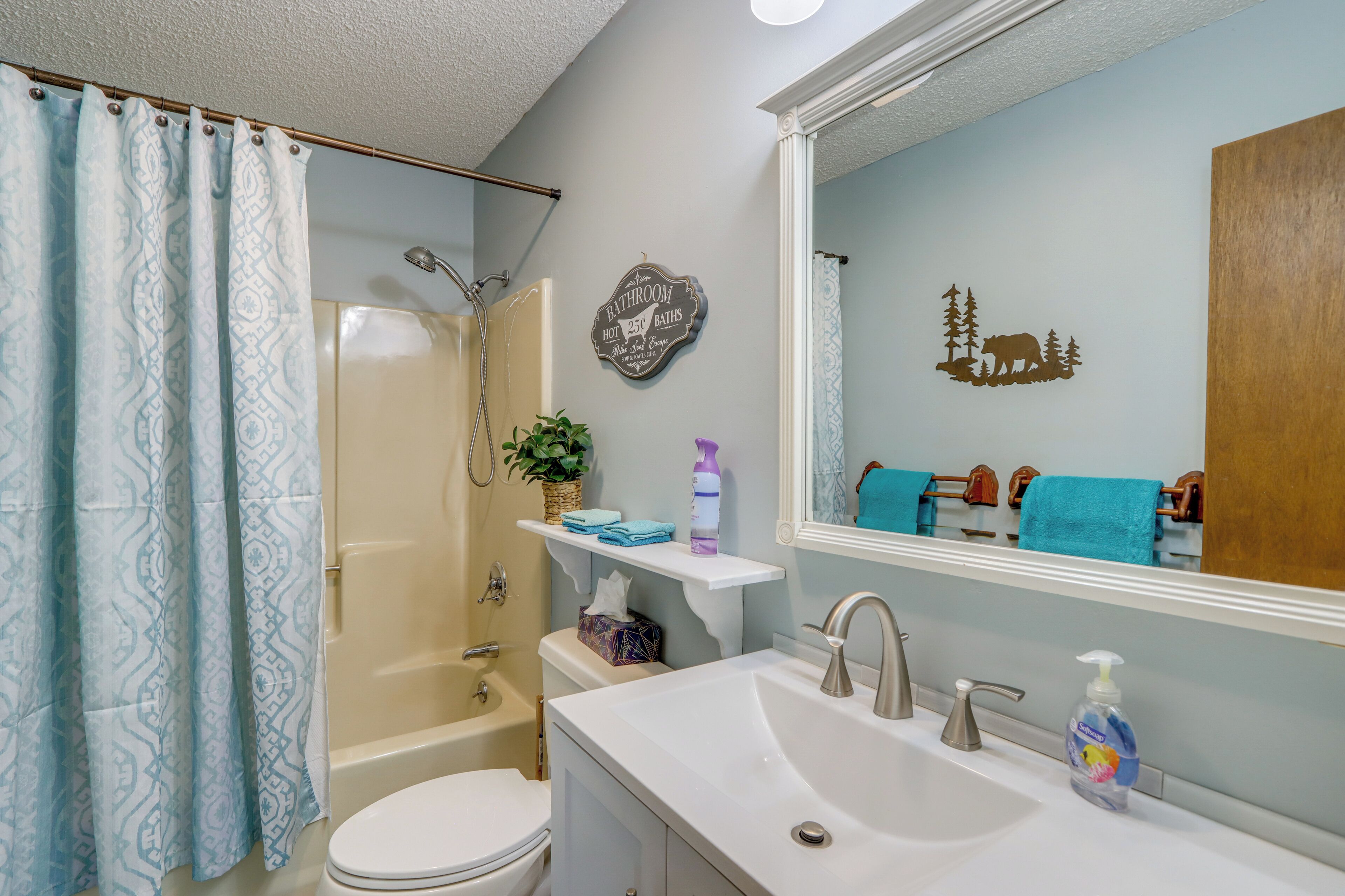 Une salle de bain équipée d’une douche, de toilettes, d’un lavabo et d’un miroir.