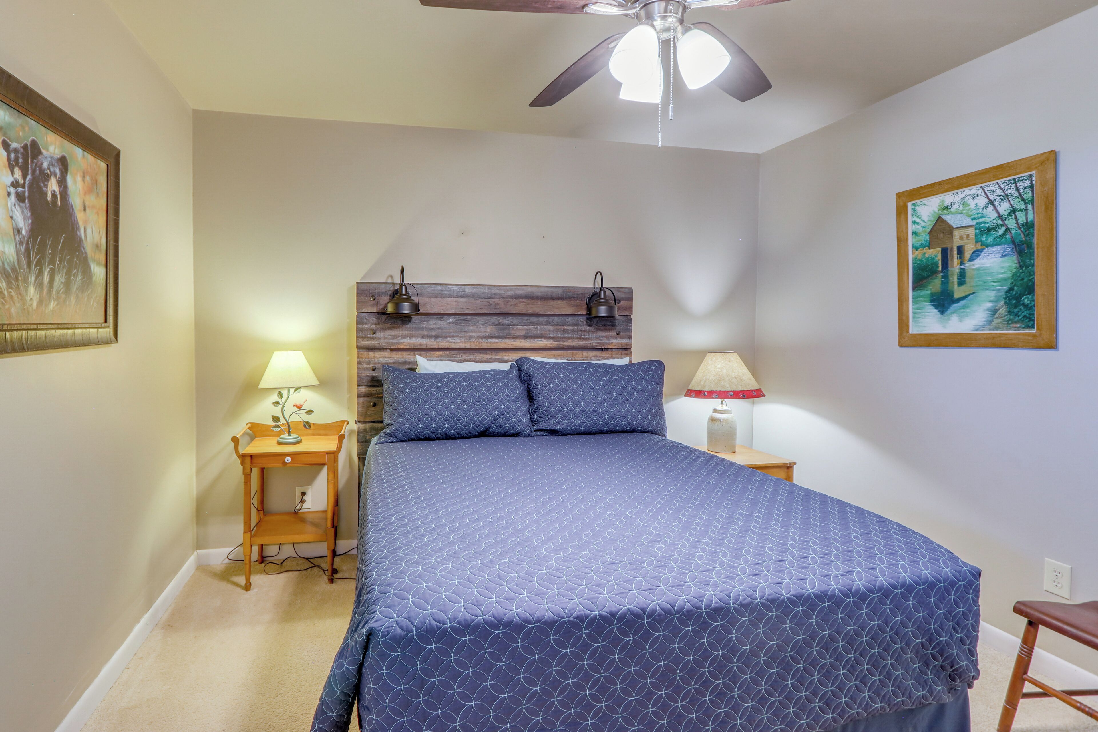 A bedroom with a bed, two bedside tables, a ceiling fan, and two wall-mounted lamps.