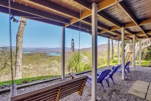 A covered outdoor seating area with a bench and chairs, overlooking a scenic landscape with mountains and a lake. - Magnificent View of Lake Chatuge & the Mountains (Young Harris)