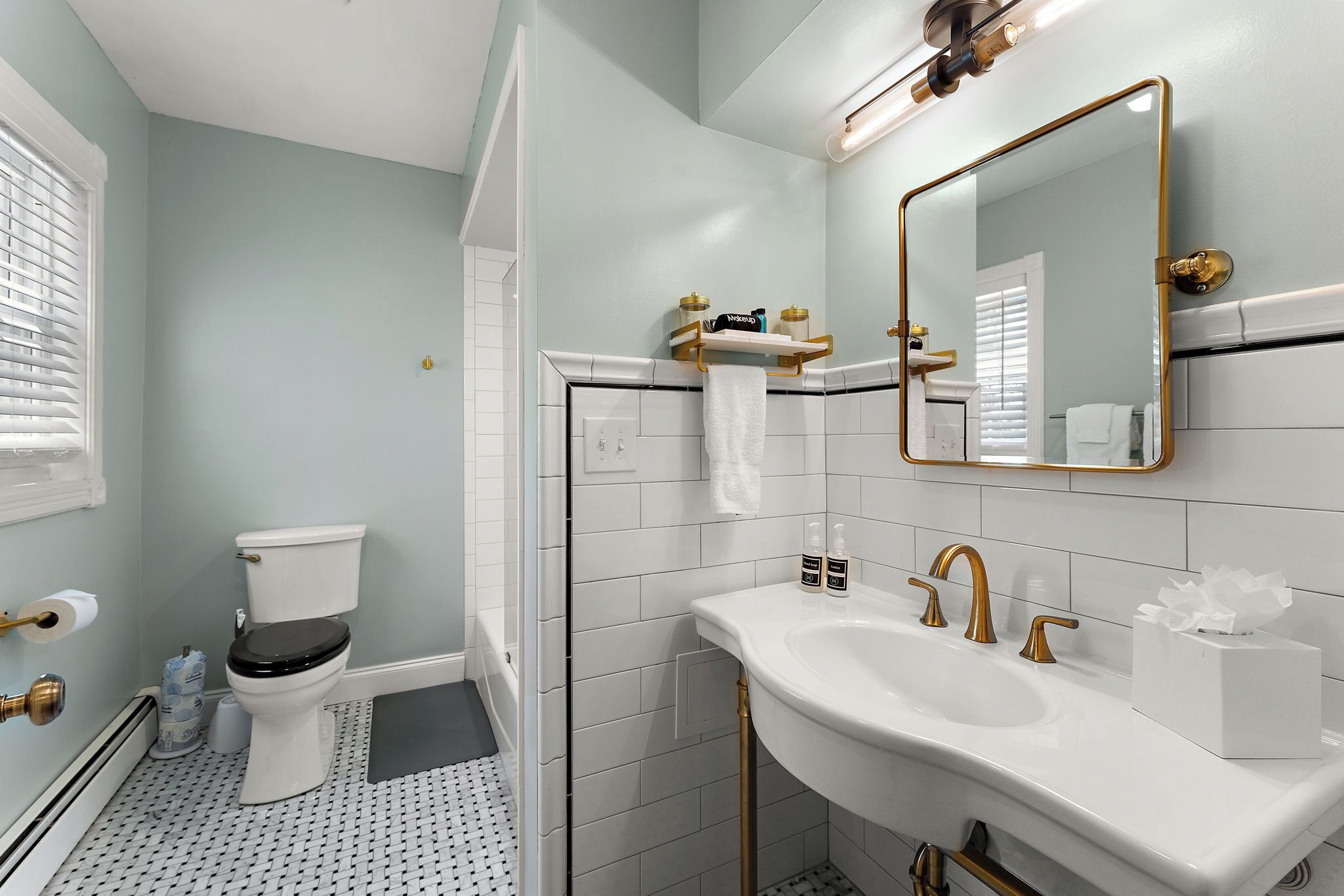 A bathroom with a toilet, sink, mirror, and towel rack.