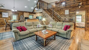 A spacious living area with a large sectional sofa, a wooden coffee table, and a staircase leading to an upper level. - Lake Barkley Fishing Getaway w/ Private Dock! (Cadiz)