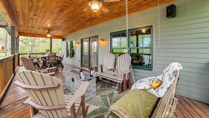 A wooden deck with Adirondack chairs, a swing chair, and a small bar area. - Lake Barkley Fishing Getaway w/ Private Dock! (Cadiz)
