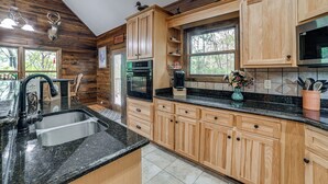 A kitchen with wooden cabinets, a sink, a stove, and a window. - Lake Barkley Fishing Getaway w/ Private Dock! (Cadiz)