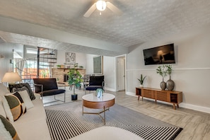 A modern living room with a spiral staircase, a flat-screen TV, and a fireplace. - Explore Atl! Chic Home Base Near Mercedes-benz (Atlanta)