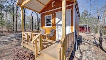 A wooden cabin with a porch, a door, and a window.