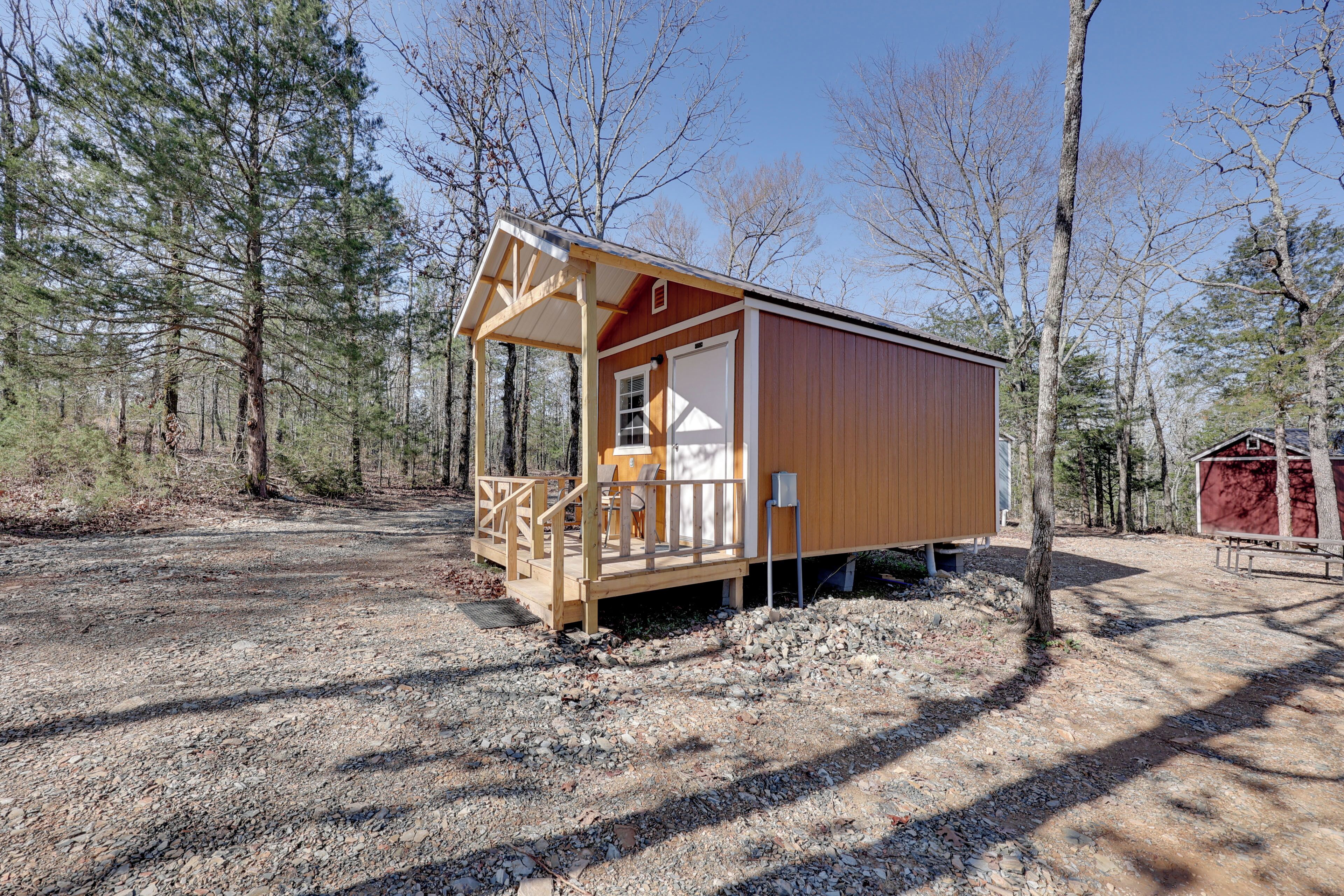 A wooden cabin with a porch, a door, and a window.