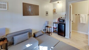 Une chambre moderne équipée d’un canapé-lit, d’une table de chevet, d’une lampe et donnant sur la cuisine.