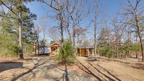 A cabin with a porch, a small shed, and a picnic table in a wooded area. - Small Family Getaway in Mena w/ Trails On-site! (Mena)