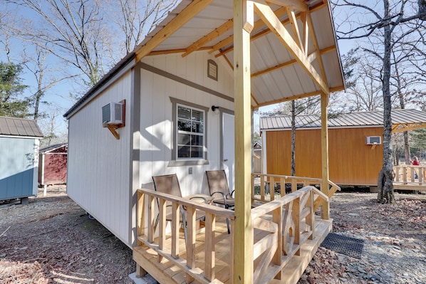 Une petite cabane avec une véranda, une fenêtre et une porte.