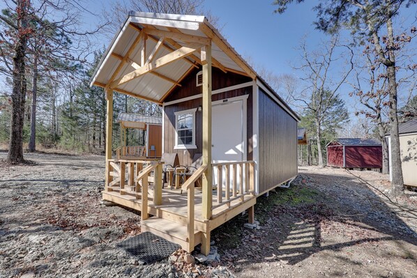 A small wooden cabin with a porch, a window, and a door.