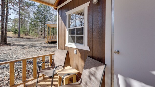 A wooden cabin with a porch, a window, and a door. - Ouachitas Adventure Base! Charming Tiny Cabin (Mena)