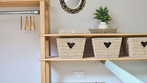 A wooden shelf unit with baskets, a mirror, and a small plant. - Stylish 2BR Home | Central Hebden Bridge Escape (Hebden Bridge)