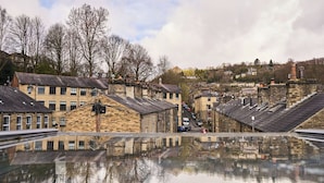 A historic town with stone buildings, a clear sky, and a reflection in a puddle. - Stylish 2BR Home | Central Hebden Bridge Escape (Hebden Bridge)