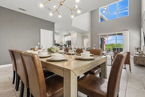 A dining area with a large wooden table set for six, surrounded by leather chairs. - 5BR•Sleeps 13•Pvt pool & spa•Free water park (Kissimmee)