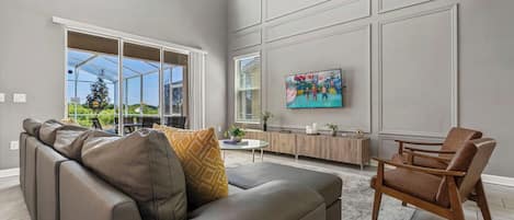 A modern living room with a sectional sofa, a wooden chair, and a painting on the wall.