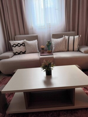 Ein Wohnzimmer mit einer Sofagarnitur, einem Couchtisch und einer kleinen Pflanze.