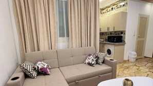 Ein Wohnzimmer mit einer Couch, einem Couchtisch und einer Küche im Hintergrund.
