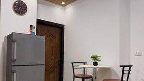 Eine Küche mit Kühlschrank, einer Uhr und einem kleinen Tisch mit St ühlen.