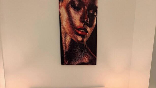 Ein ordentlich bezogenes Bett mit einer grauen Tagesdecke, zwei Kissen und zwei gefalteten Handtüchern. Auf den weißen Nachttischen stehen je eine Nachttischlampe.