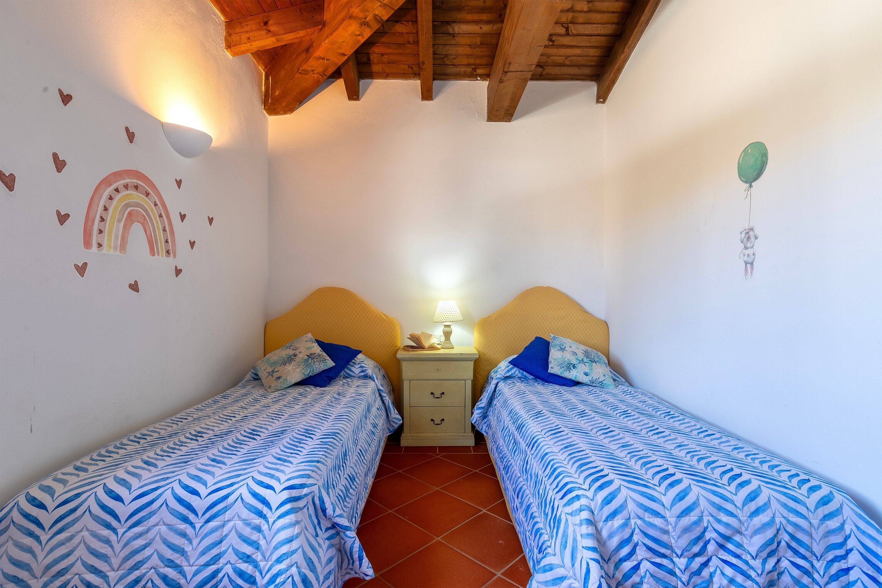 Een slaapkamer met twee bedden, een nachtkastje, een lamp en een wanddecoratie.