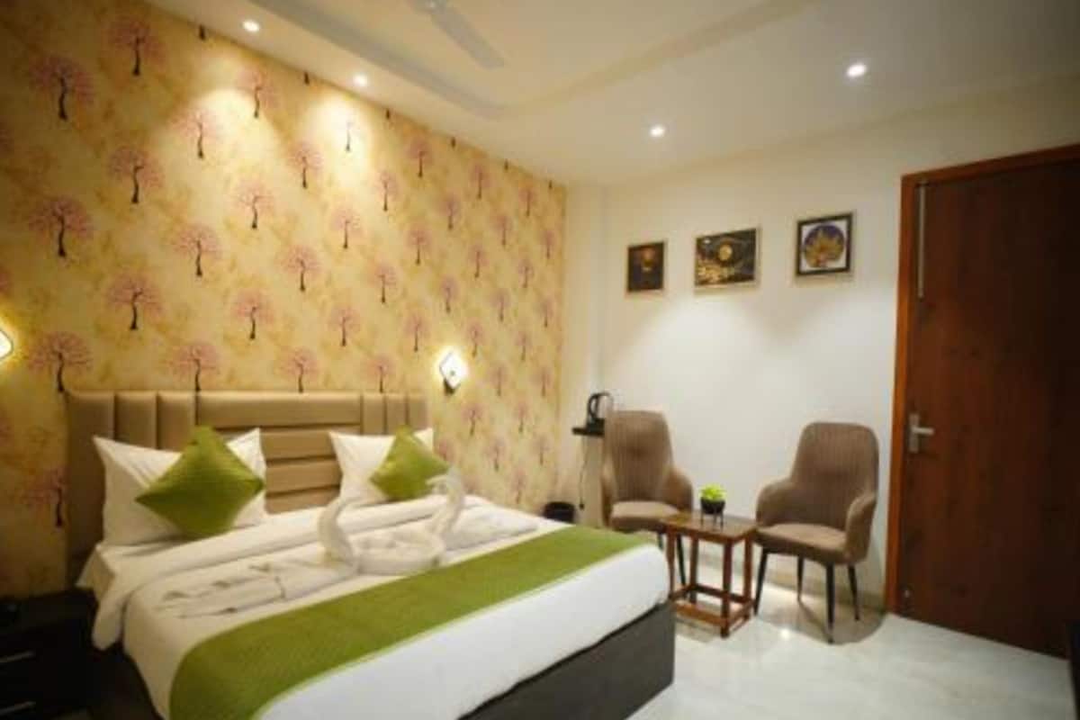 A hotel room with a bed, two armchairs, a small table, and a door.