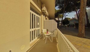 A balcony with a white chair, a small table, and a potted plant. - Coastal Home Between the Beach and the Center (Lignano Sabbiadoro)