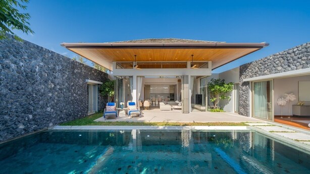 Een modern huis met een zwembad, stenen muren en een overdekt terras.