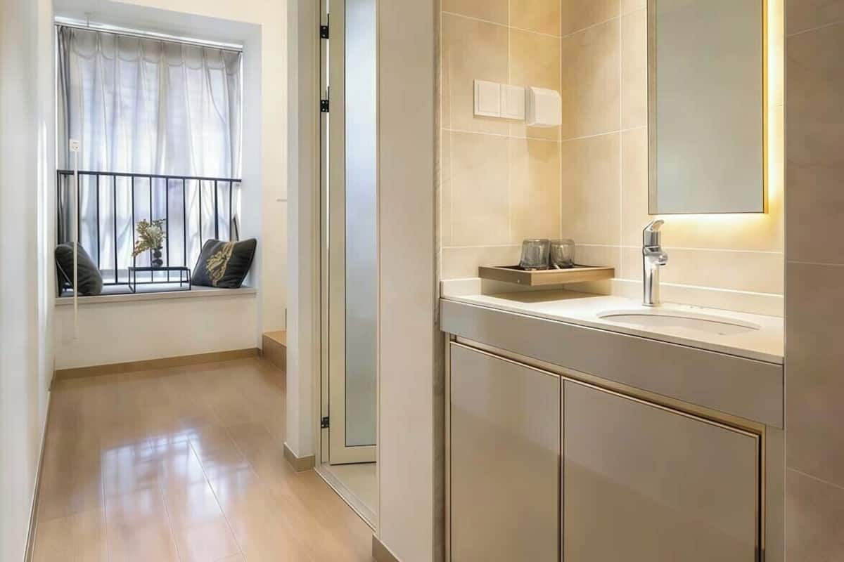 A modern bathroom with a large mirror, a sink, and a window with a view.
