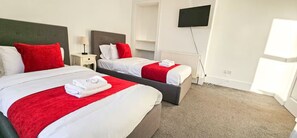 Una camera d'albergo con due letti, una televisione e un termosifone.
