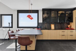Eine moderne Küche mit einer großen Kochinsel, schwarzen Schränken und Blick zum Himmel.