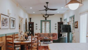 A dining area with a wooden table and chairs, a sofa, and a ceiling fan. - Charming cottage on 8 acres of peace & tranquility just a short drive from town. (Boaz)
