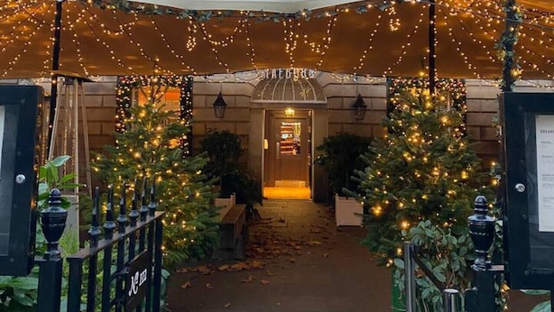 L’entrée d’un hôtel, avec un passage couvert, un sapin de Noël et une enseigne indiquant « Hôtel ».