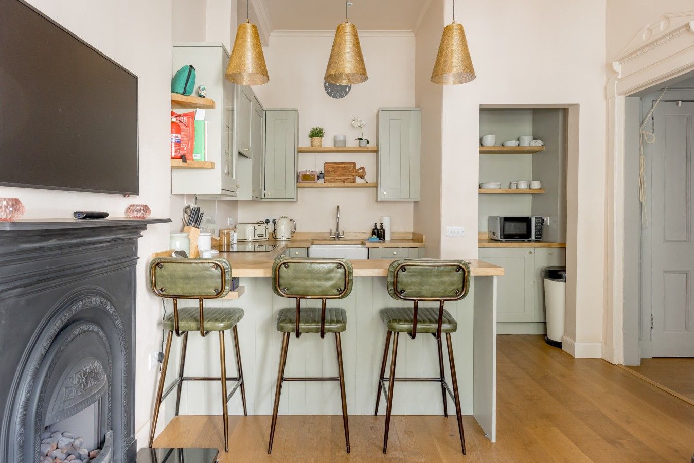 A kitchen with a central island, bar stools, pendant lights, and a fireplace.