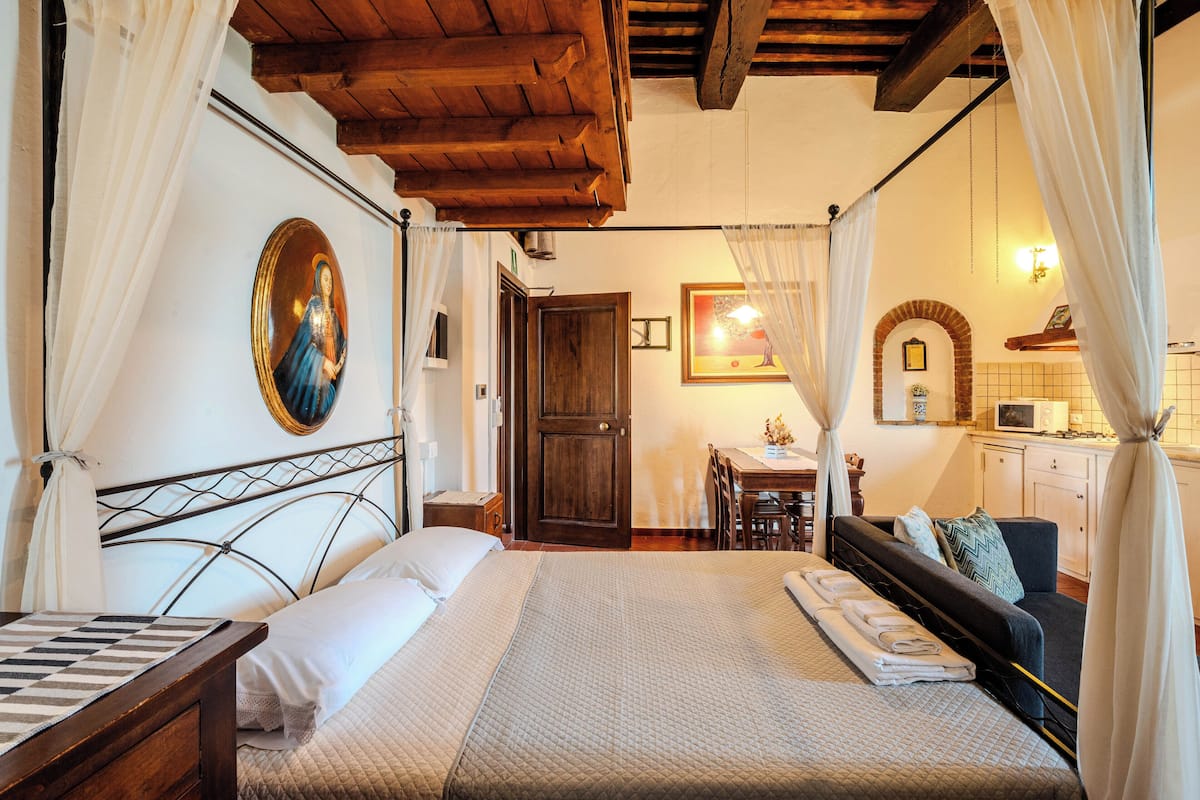 A bedroom with a bed, a wooden headboard, a nightstand, a desk, and a chair.