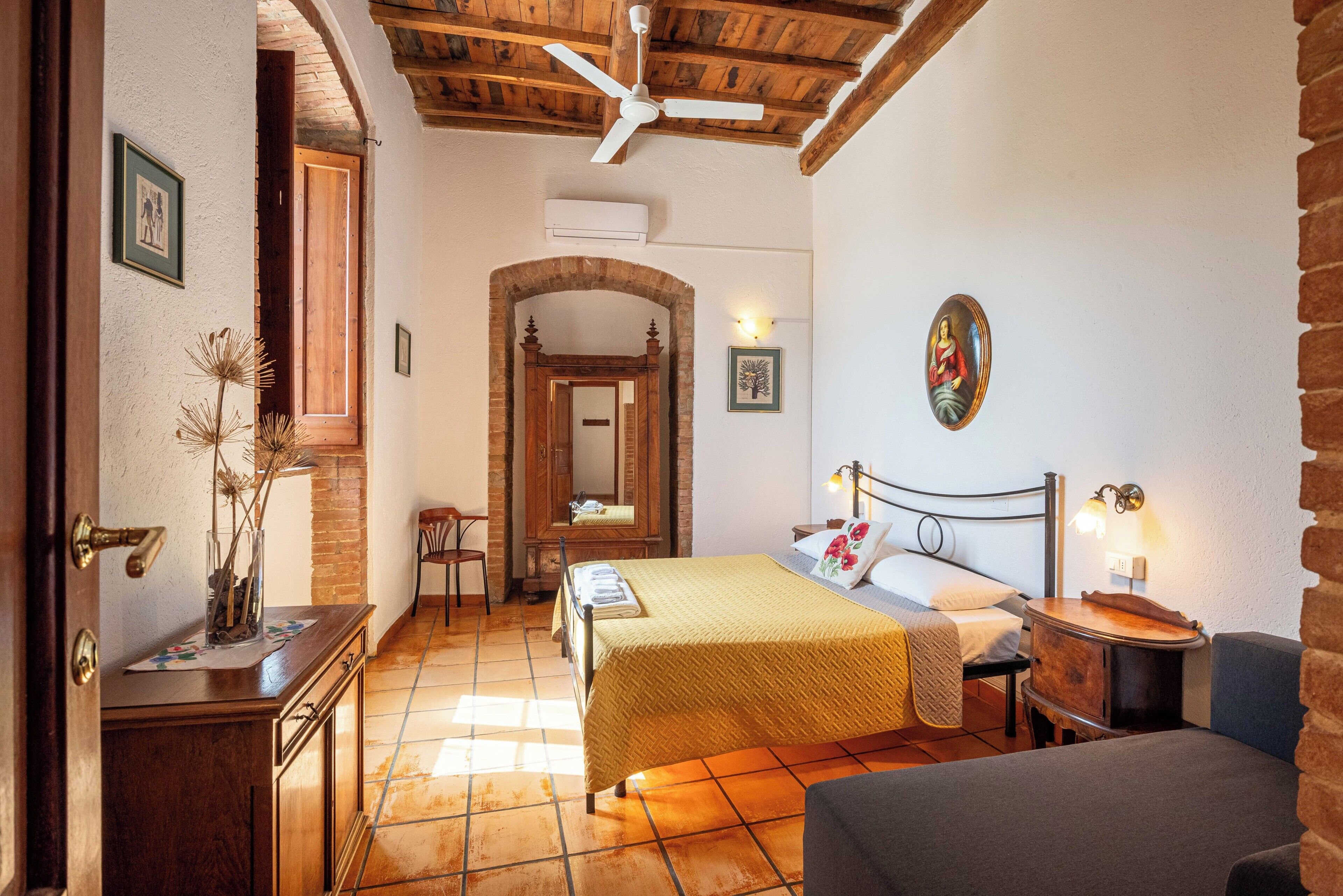 Ein Schlafzimmer mit Bett, Stuhl, Schreibtisch und Spiegel.