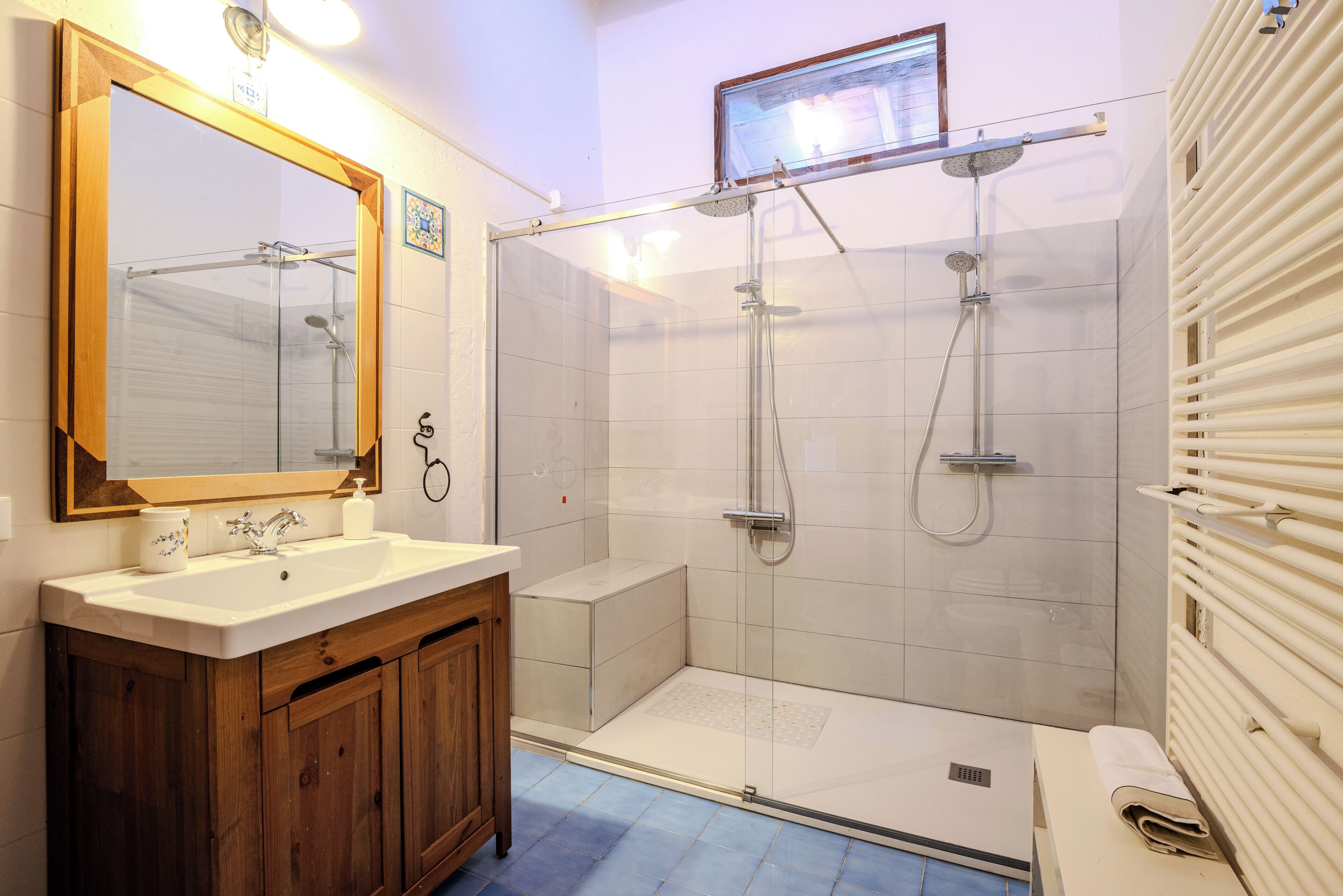 Een moderne badkamer met een douchecabine van glas, een houten wastafelmeubel en een grote spiegel.