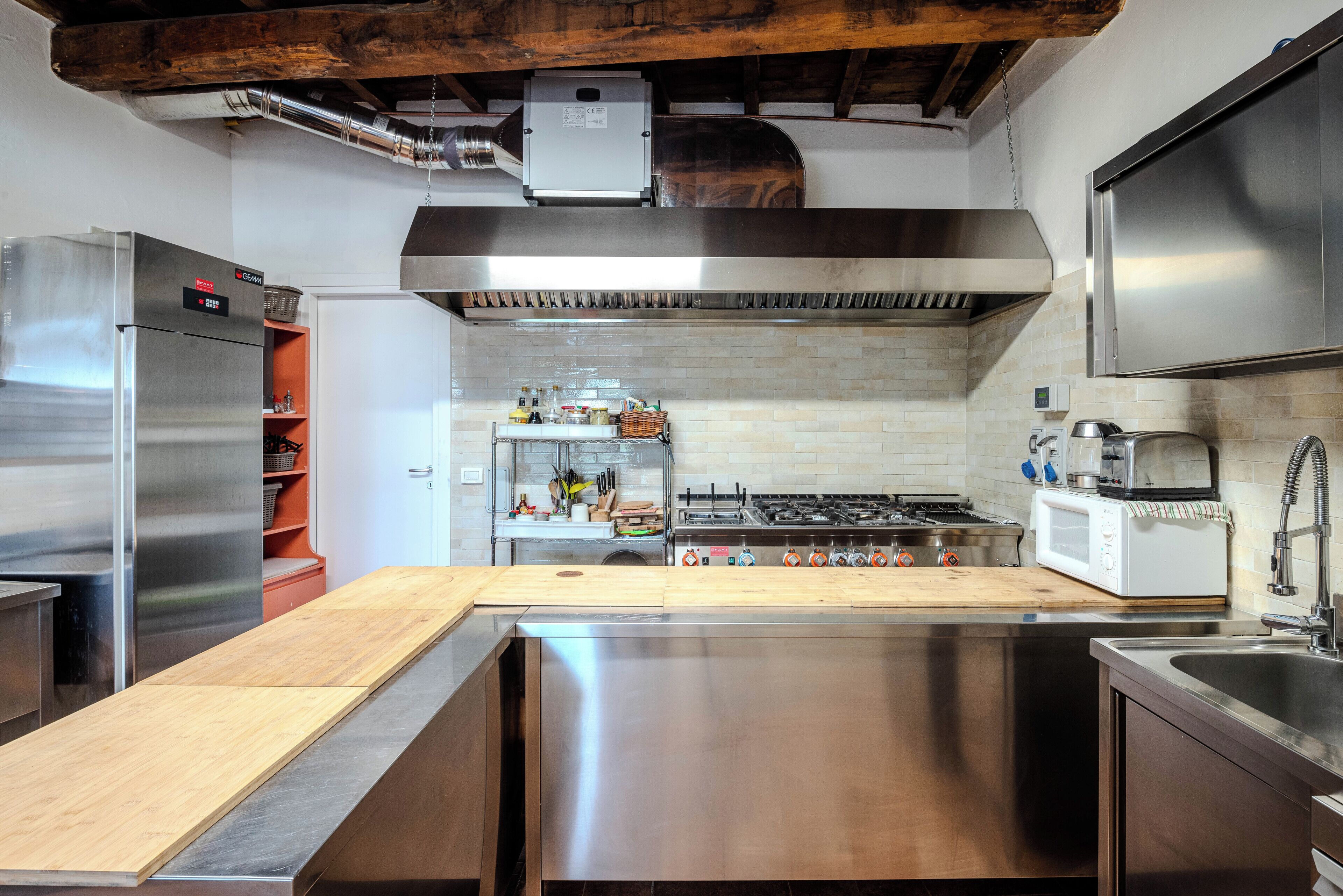 Una cocina moderna con electrodomésticos de acero inoxidable, encimera de madera y salpicadero de azulejos.