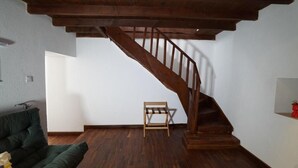 A room with a wooden staircase, a green sofa, and a small wooden chair. - Muyo House (Urla)