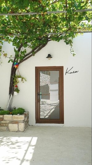 A door with a glass panel, a wall-mounted light, and a signature above it. - Muyo House (Urla)