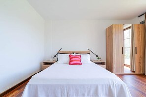 A bedroom with a bed, nightstands, a wooden wardrobe, and a window. - Muyo House (Urla)