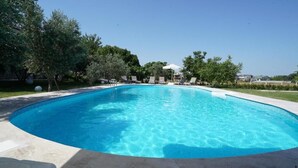 A clear swimming pool surrounded by lounge chairs and trees. - Muyo House (Urla)