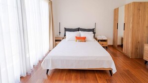 A bedroom with a bed, nightstands, a wardrobe, and sheer curtains. - Muyo House (Urla)