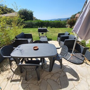 A patio with a table and chairs, a grill, and a view of the landscape. - Air-Conditioned Villa Apartment with Ocean View and Parking, 3-Star (VIGGIANELLO)