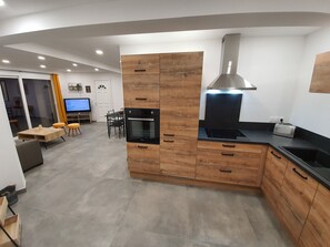 Moderni keittiö, jossa on puiset kaapit, sisäänrakennettu uuni, liesi ja pesuallas.