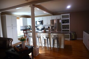 A modern kitchen with white cabinets, stainless steel appliances, and a central island with bar stools.