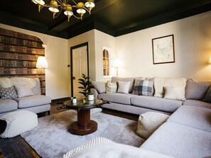 A living room with a sofa set, a coffee table, a bookshelf, and a door. - The Admiral's Home (Whitehaven)